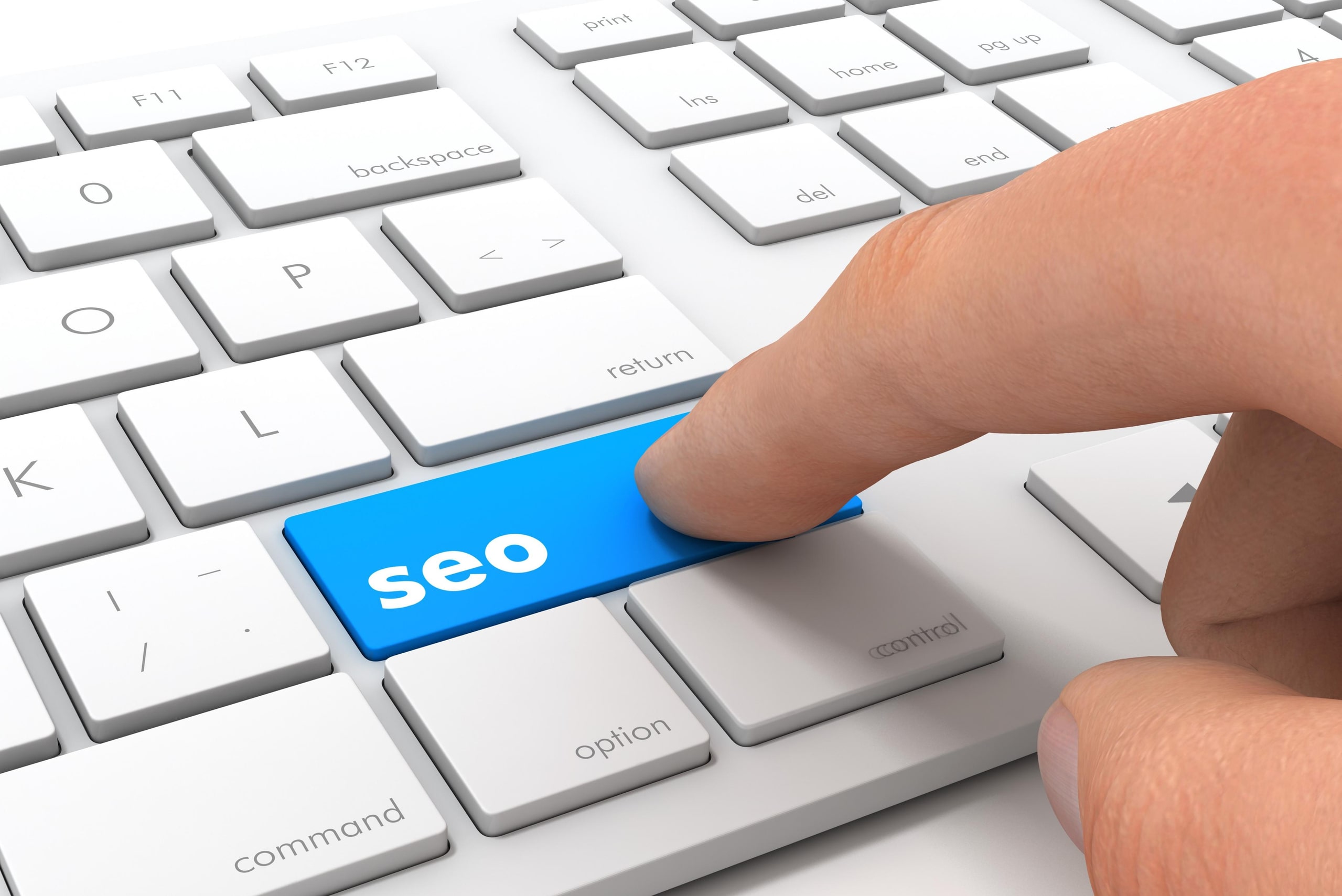 Primer plano de un teclado blanco con una tecla azul destacada con la palabra "SEO", simbolizando la importancia del SEO local para mejorar la visibilidad y el posicionamiento de un negocio en los motores de búsqueda.