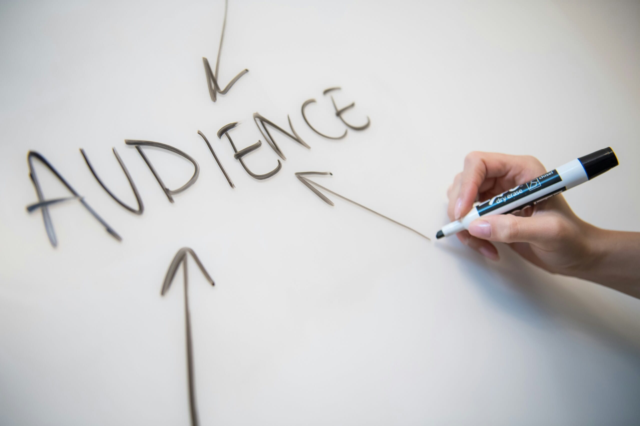 Persona escribiendo “audience” en una pizarra, imagen relacionada con métricas para medir el éxito del influencer marketing y la análisis de audiencia.