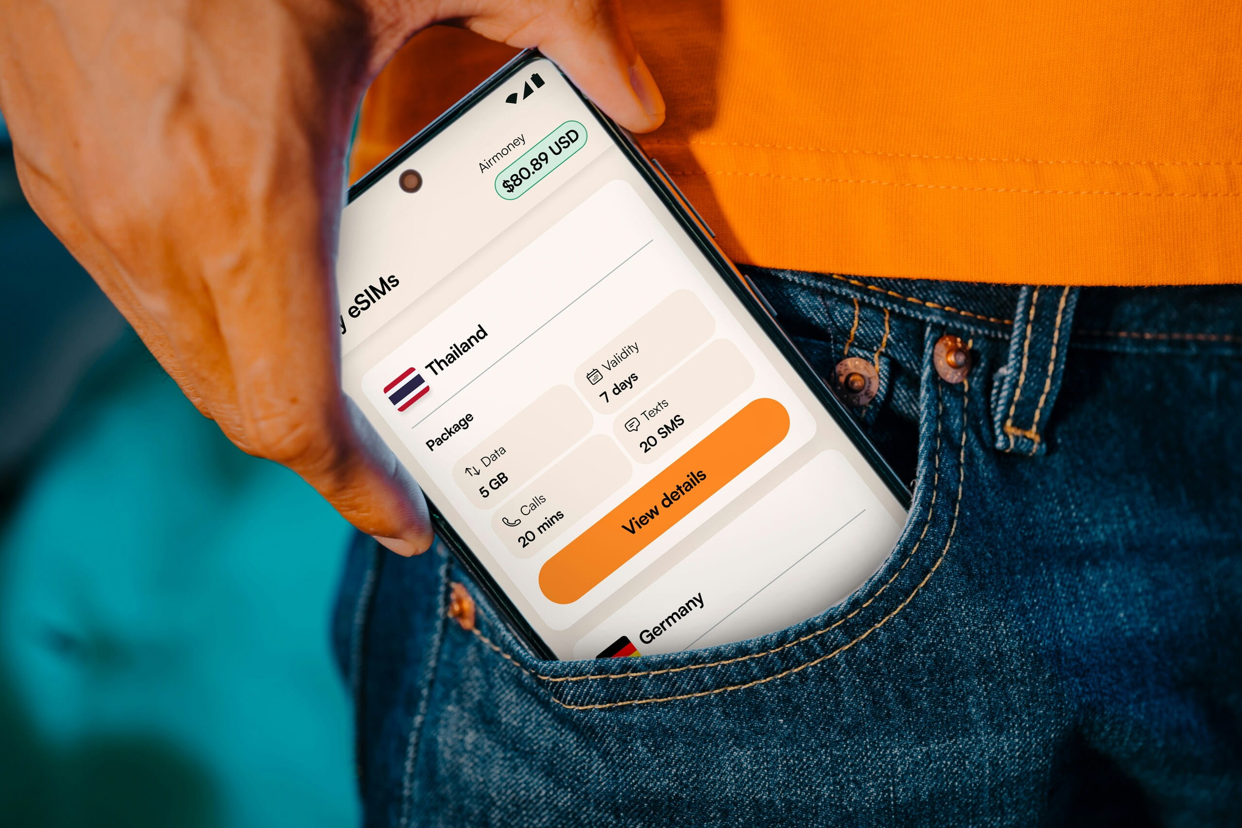 Mano guardando un teléfono en el bolsillo, muestra saldo en USD por pasarelas de pago internacionales.