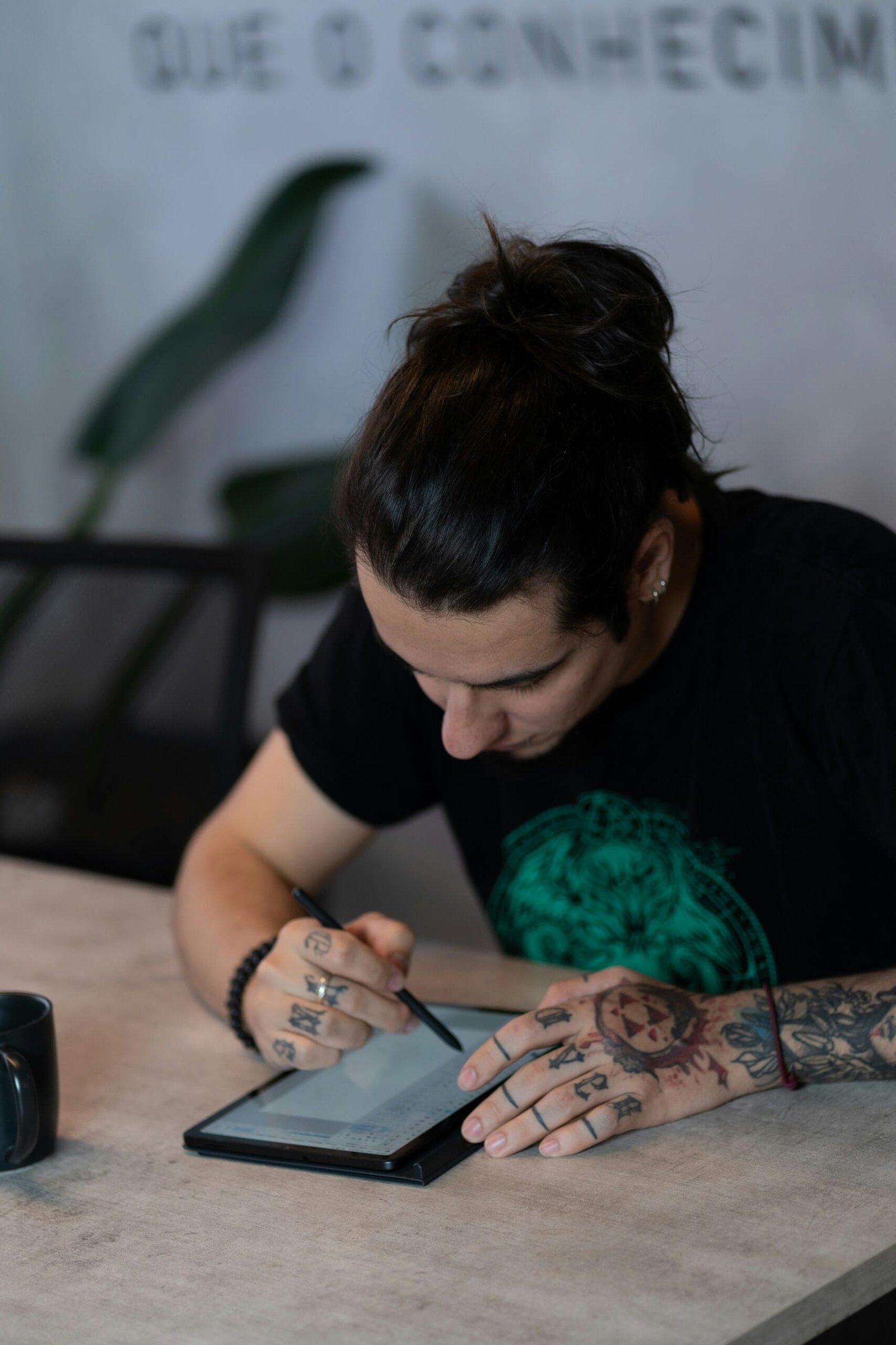 Hombre tatuado usando tableta y lápiz óptico mientras crea Comparativas y guías de compra para su contenido digital.