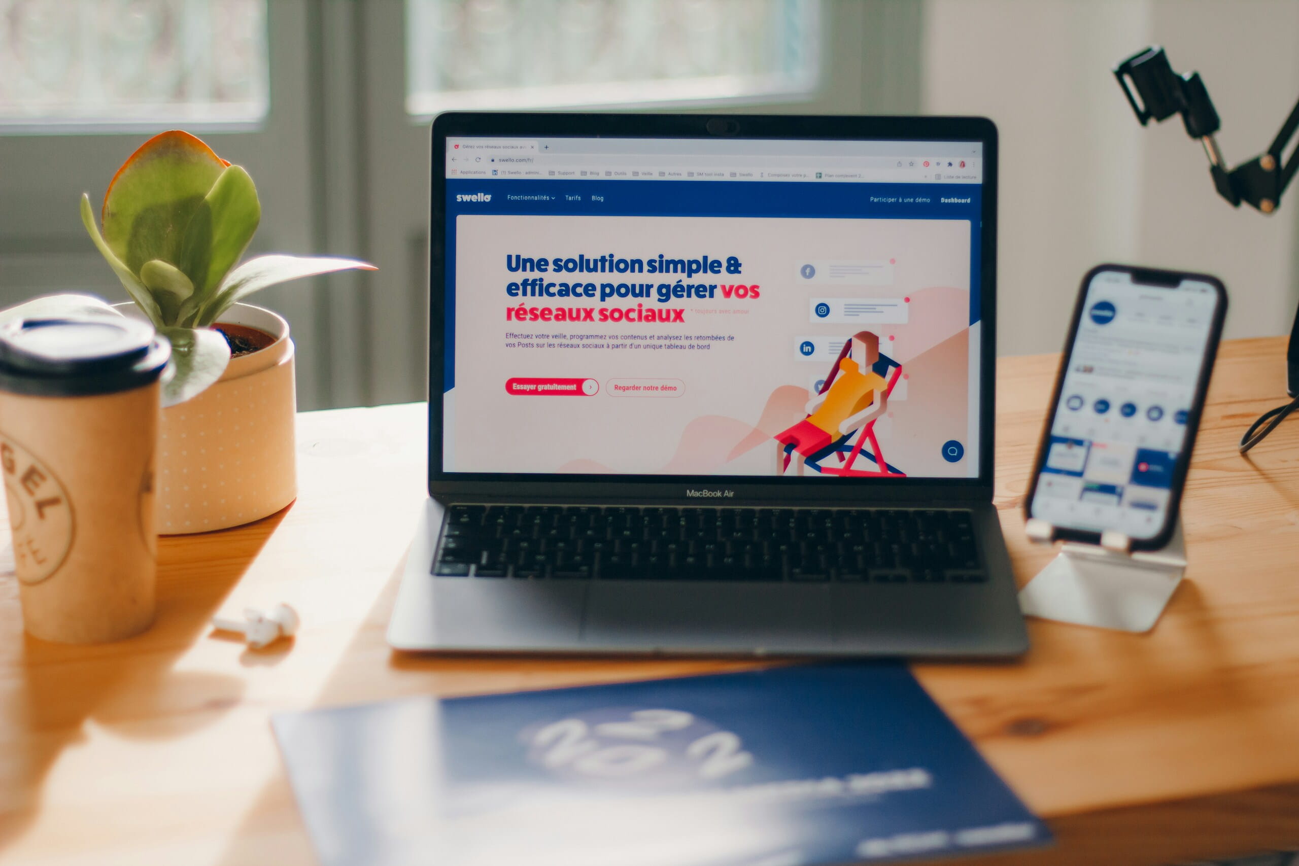 Escritorio con portátil y móvil mostrando herramientas digitales para Seguimiento y medición del ROI en ecommerce, junto a una planta y café.