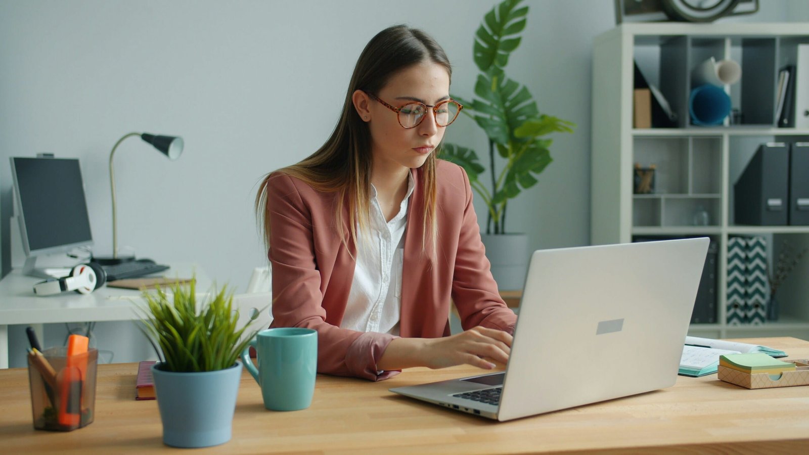 Mujer profesional teclea en laptop en oficina mientras selecciona el entorno y la audiencia adecuados para su marketing.