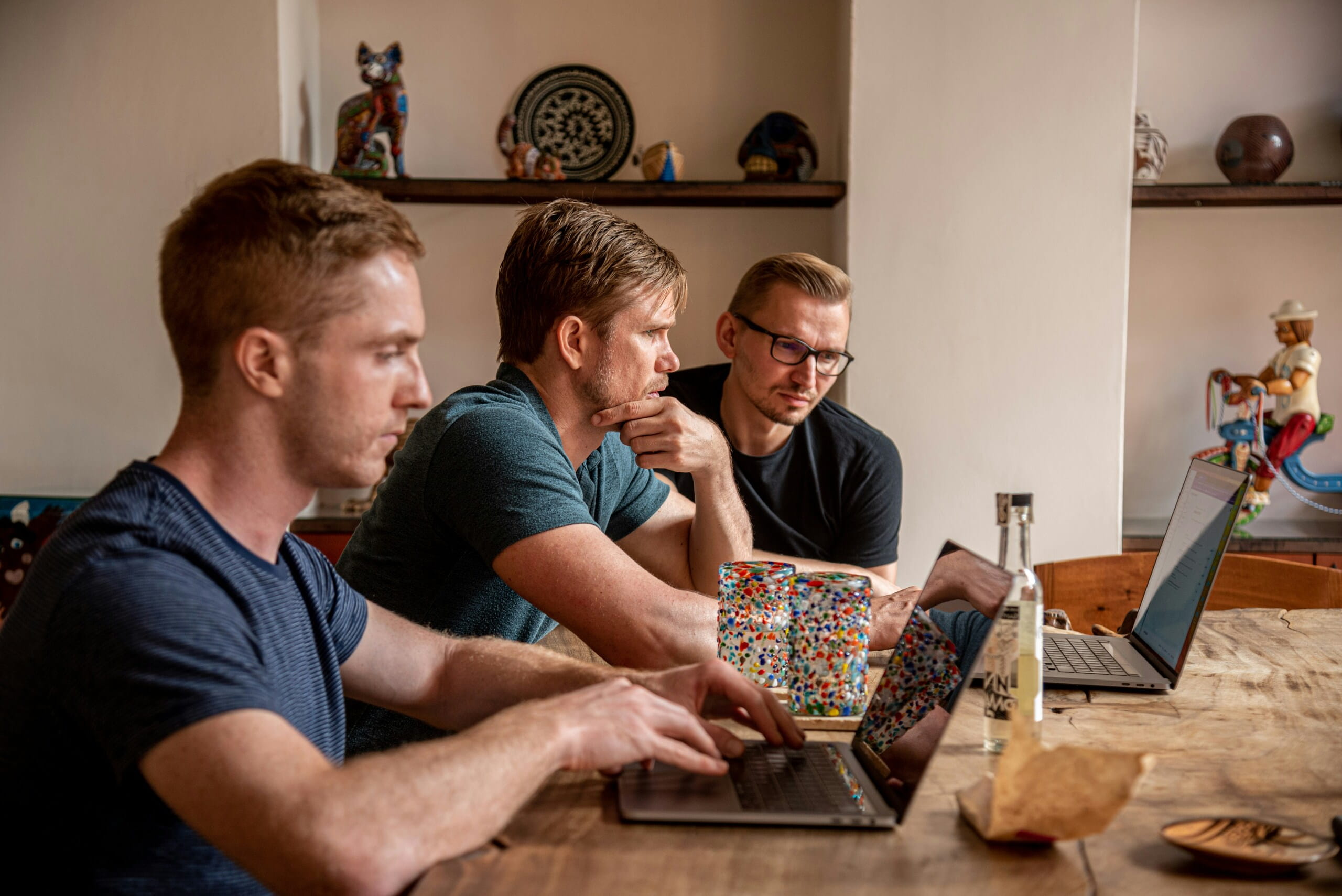 Tres hombres trabajan concentrados con portátiles en una mesa, reflejando Storytelling emocional en una sesión colaborativa.